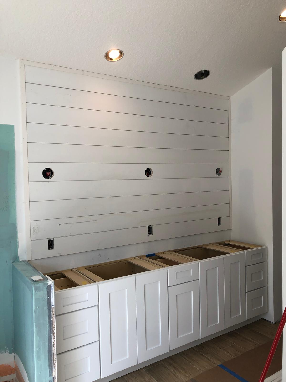 Bathroom vanity wall before final finishes with cabinets and shiplap installed