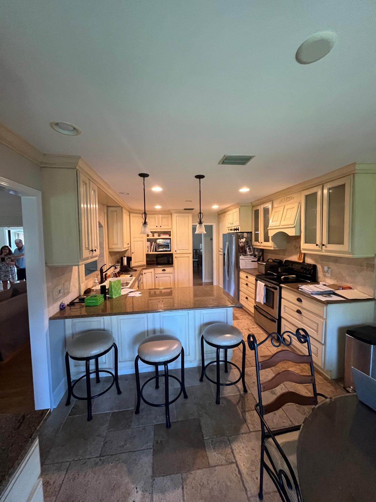 Kitchen before remodel with older cabinets, island, counters, and flooring
