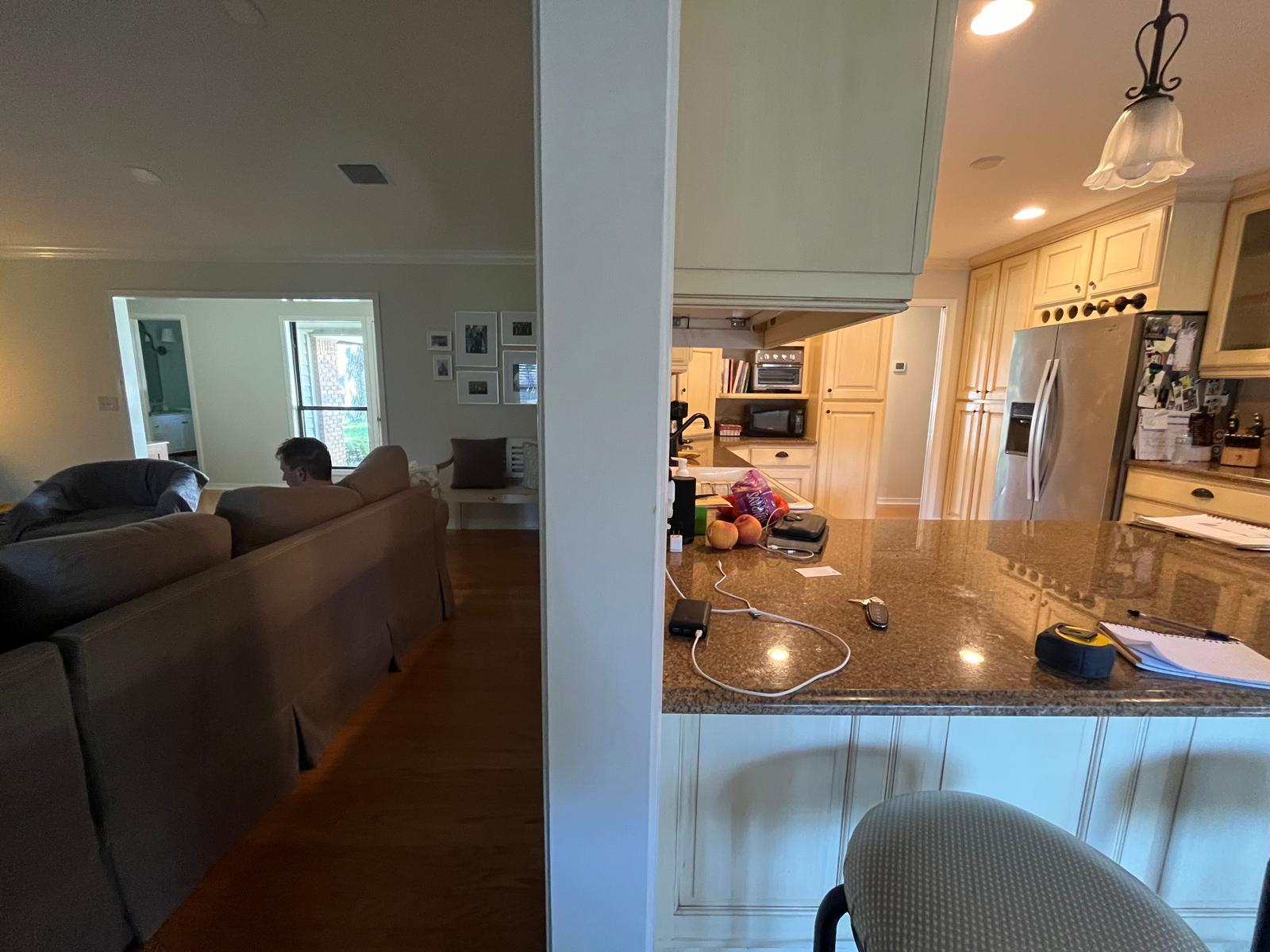 Kitchen before remodel viewed from the living area with older cabinetry and counters